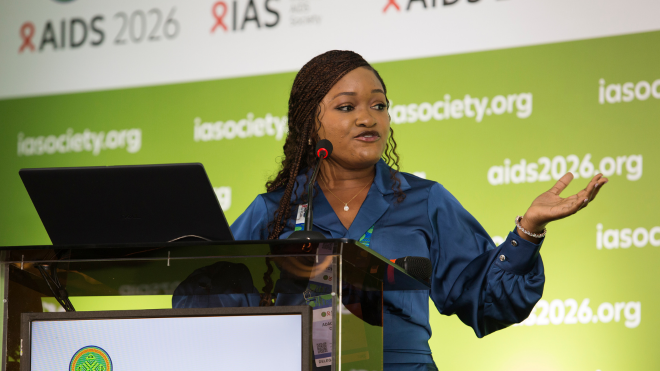 Adaobi Lisa Olisa at AIDS 2026. She is standing at a lectern talking into a microphone.