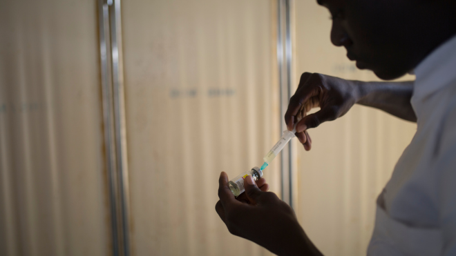 A health practitioner prepares an injection.