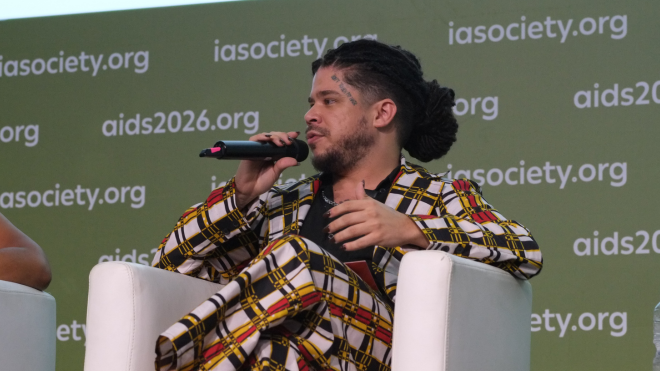 Thiago Jerohan Albuquerque da Cruz at AIDS 2026. He is sitting down and talking into a microphone at a press conference.
