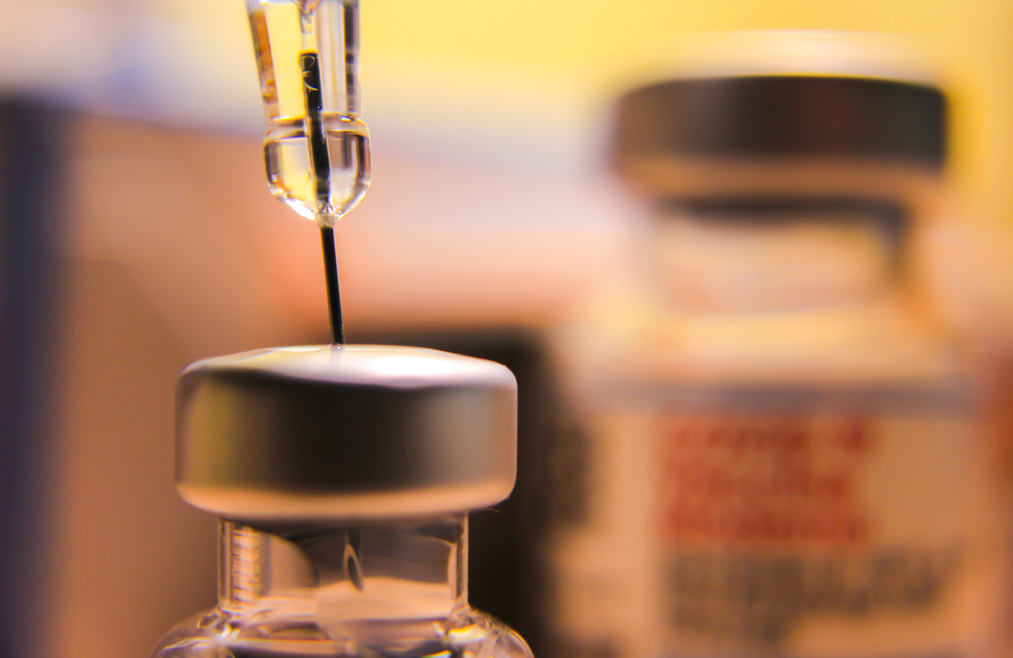 A close-up of a syringe and a vaccine bottle.