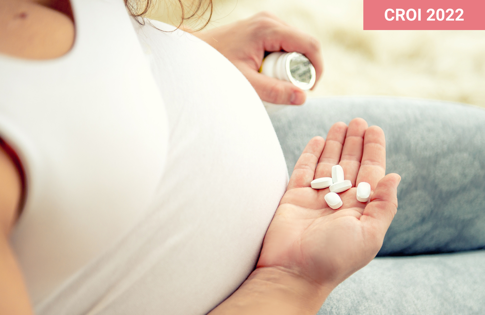 A pregnant woman holding pills.