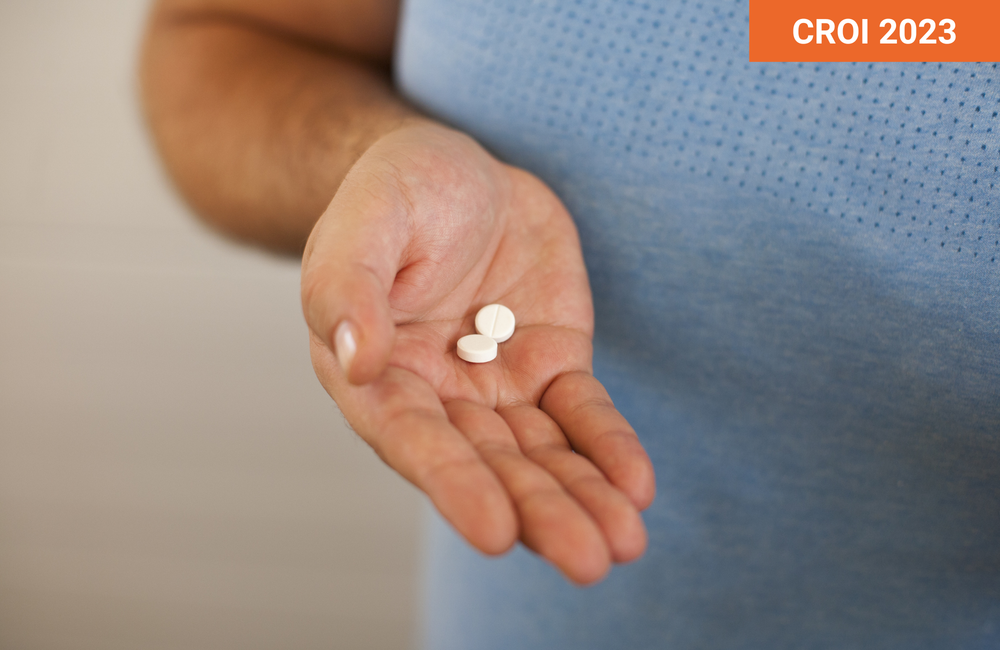 Man holding two small white pills in his hand.