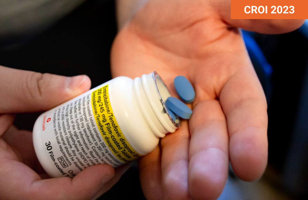 Two blue pills being tipped from a pill bottle into a hand.