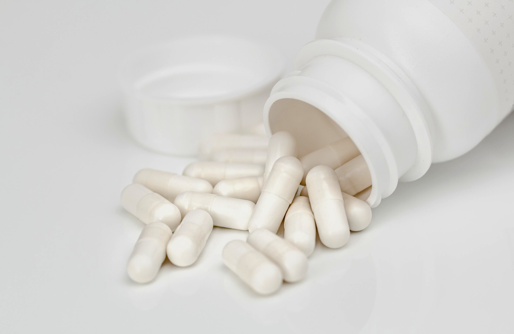 Image: Pixabay A white pill bottle is tipped over with white pills spilling out on to a table.