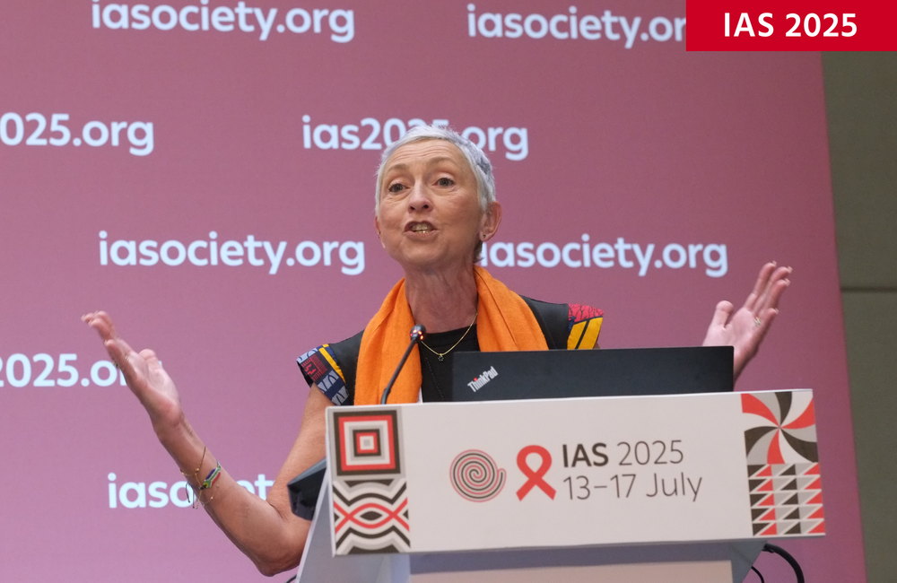 Professor Linda-Gail Bekker at IAS 2025. Image: Roger Pebody. Professor Linda-Gail Bekker at IAS 2025. She is talking at a podium and has short grey hair and has an orange scarf around her neck.