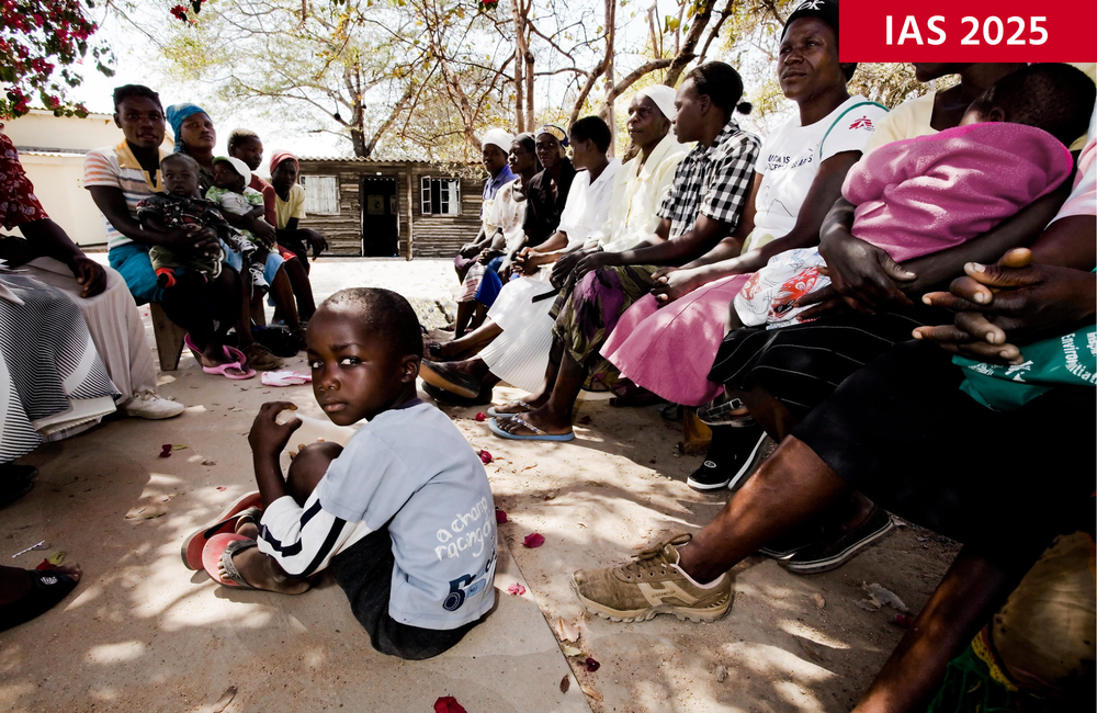 Image: Elizabeth Glaser Pediatric AIDS Foundation/DFID. Creative Commons licence. Image is for illustrative purposes only. A young African boy sits on the ground, looking over his shoulder. A group of people (adults and children) sit either side of him on benches.