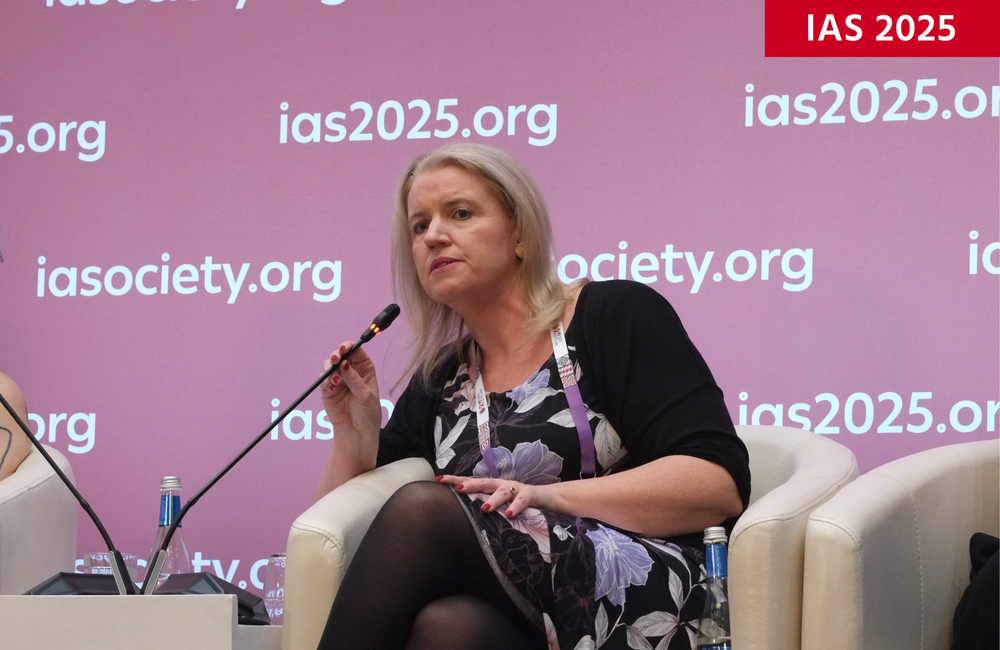 Dr Katherine Gill at IAS 2025. She is sitting on a grey chair talking into a microphone.