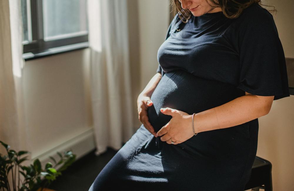 A pregnant woman holds her stomach.