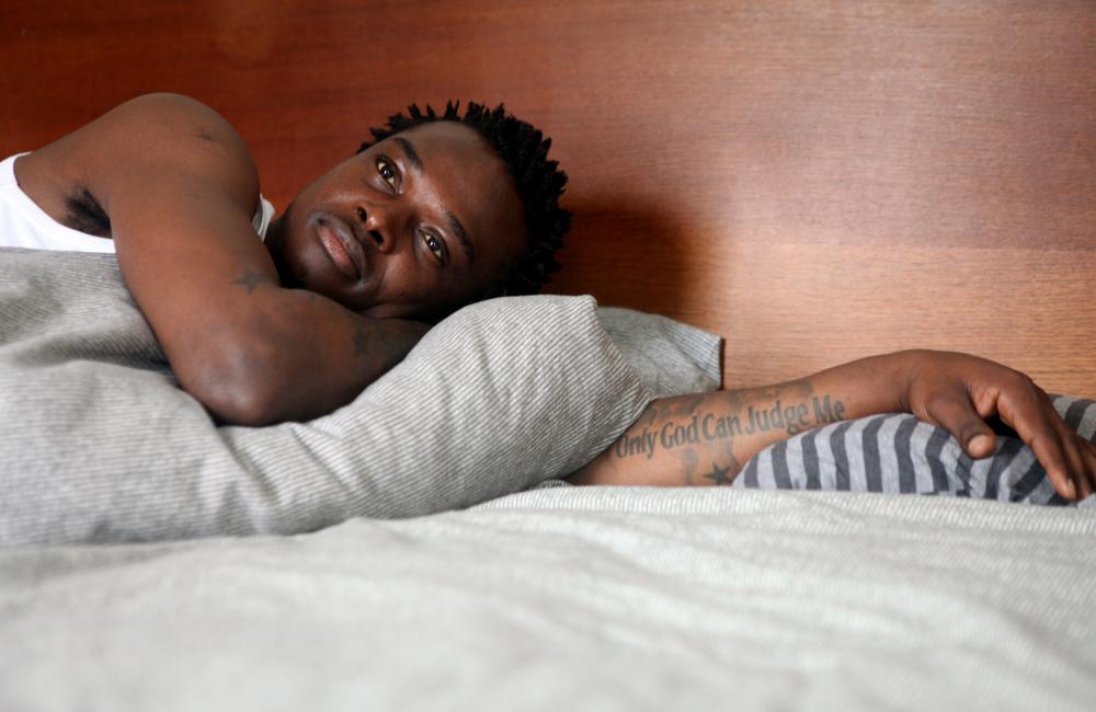 A man lies in bed, looking thoughtful.