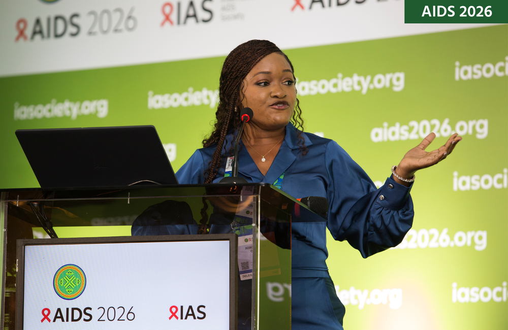 Adaobi Lisa Olisa at AIDS 2026. She is standing at a lectern talking into a microphone.