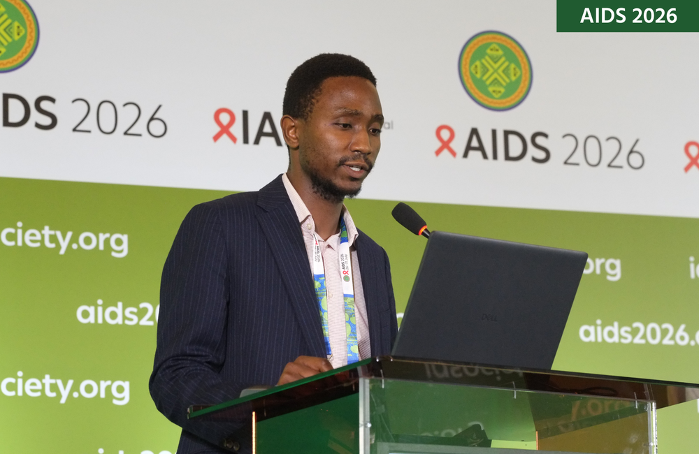 Dr John Fly Phiri at AIDS 2026. He is standing at a lectern, talking into a microphone.